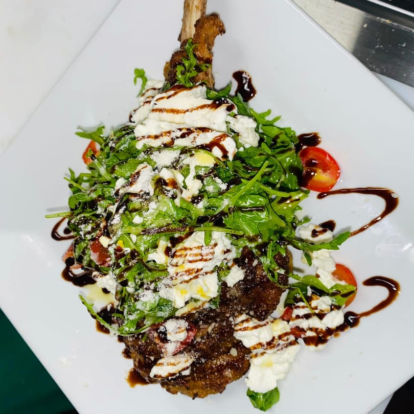 Favio's Trattoria's veal chop topped with arugula, cherry tomatoes, ricotta, and balsamic glaze.