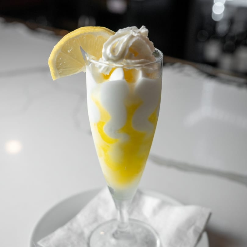 Favio's Trattoria's lemon sorbetto with whipped cream and a lemon slice on a white counter.